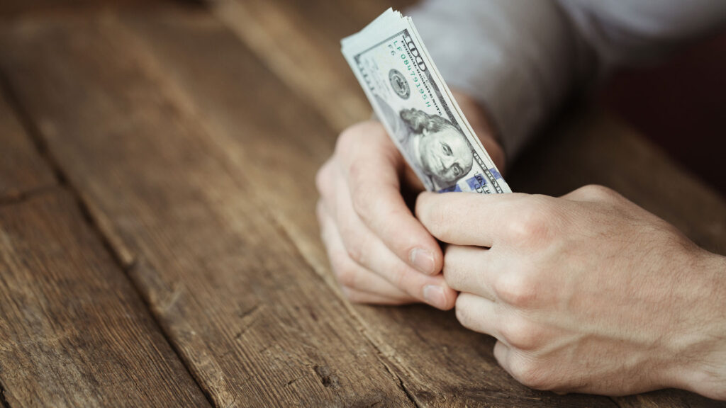 hands holding money on a wooden table