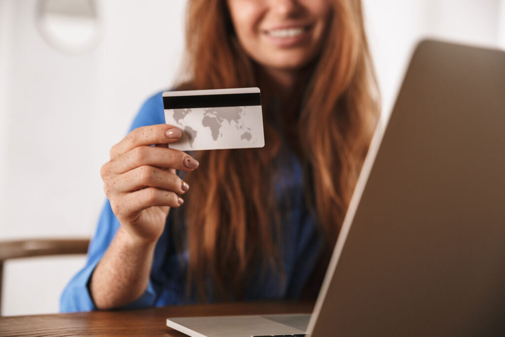 woman holding credit card next to laptop