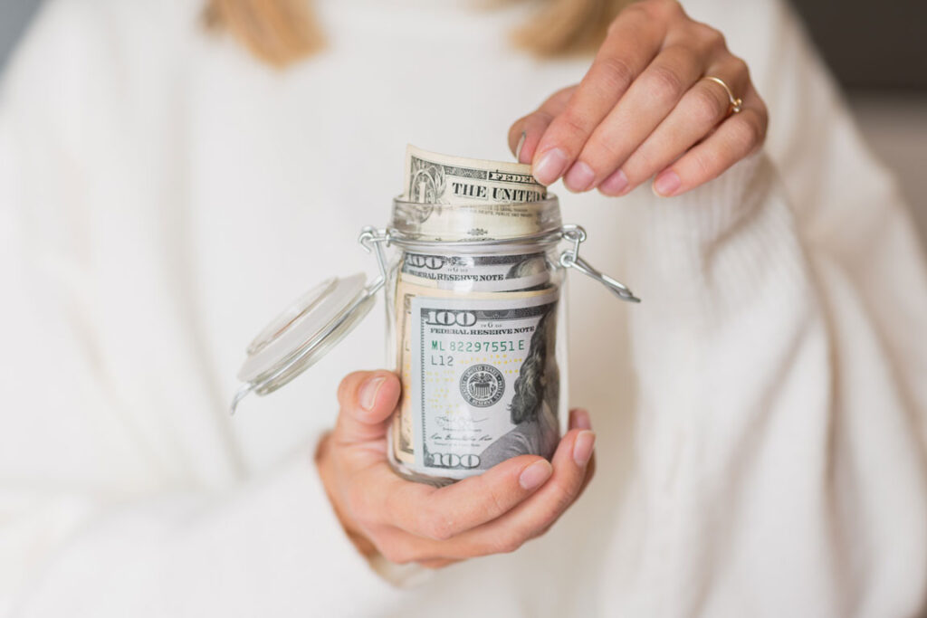 woman holding glass jar filled with American dollars
