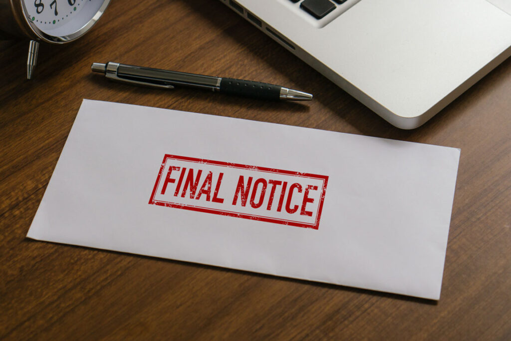 final notice envelope next to a clock, a pen, and a laptop