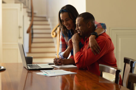 African American couple smiling and looking at their laptop