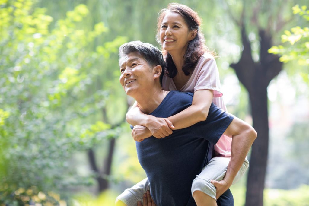 elderly people walking through woods smiling